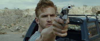 Movie still from “The Guest” (2014), directed by Adam Wingard – A person holding a gun; Close Up shot, Over the shoulder angle