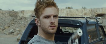 Movie still from “The Guest” (2014), directed by Adam Wingard – A person with a car in the background; Close Up shot, Over the shoulder angle