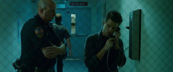 Movie still from “The Guest” (2014), directed by Adam Wingard – A man talking on a cell phone while standing next to another man; Medium shot, Low angle