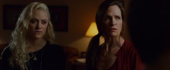 Movie still from “The Guest” (2014), directed by Adam Wingard – A woman standing next to another woman in a living room; Close Up shot, Over the shoulder angle