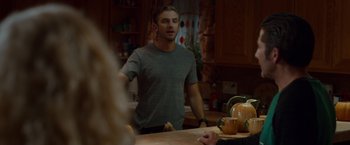Movie still from “The Guest” (2014), directed by Adam Wingard – A man standing in front of a table with food on top of it; Medium shot, Over the shoulder angle