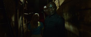 Movie still from “The Guest” (2014), directed by Adam Wingard – A man and a woman standing next to each other in a dark room; Medium shot, Over the shoulder angle