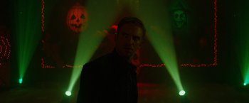 Movie still from “The Guest” (2014), directed by Adam Wingard – A man standing in front of green lights; Close Up shot, Low angle