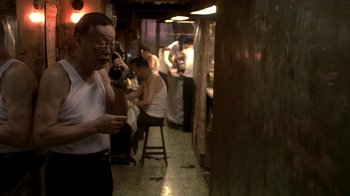 Movie still from “The Hand” (2004), directed by Kar-Wai Wong – A man talking on a cell phone while standing in front of a group of people; Medium shot, High angle