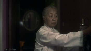 Movie still from “The Hand” (2004), directed by Kar-Wai Wong – An older woman in a white shirt is holding a knife; Close Up shot, Low angle