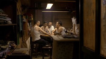 Movie still from “The Hand” (2004), directed by Kar-Wai Wong – A group of people sitting around a table; Wide shot, High angle