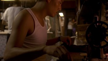 Movie still from “The Hand” (2004), directed by Kar-Wai Wong – A man in a white tank top is sitting at a table; Medium shot, Low angle
