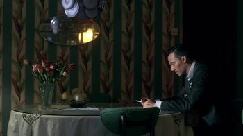 Movie still from “The Hand” (2004), directed by Kar-Wai Wong – A man sitting at a table with a cigarette in his mouth; Medium shot, High angle