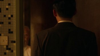 Movie still from “The Hand” (2004), directed by Kar-Wai Wong – A man wearing a suit and tie standing in front of a mirror; Medium shot, Over the shoulder angle