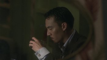 Movie still from “The Hand” (2004), directed by Kar-Wai Wong – A man in a suit looking at his cell phone; Close Up shot, Low angle
