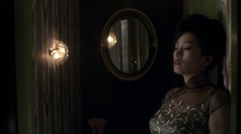 Movie still from “The Hand” (2004), directed by Kar-Wai Wong – A woman standing in front of a mirror in a dark room; Medium shot, Over the shoulder angle