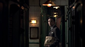 Movie still from “The Hand” (2004), directed by Kar-Wai Wong – A man in a suit holding a paper bag; Medium shot, Low angle