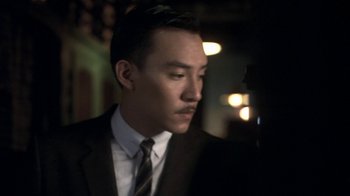 Movie still from “The Hand” (2004), directed by Kar-Wai Wong – A man wearing a suit and tie in the dark; Close Up shot, Low angle
