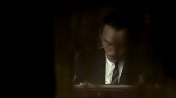 Movie still from “The Hand” (2004), directed by Kar-Wai Wong – A man wearing a suit and tie looking down at a computer screen; Close Up shot, Low angle