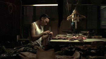 Movie still from “The Hand” (2004), directed by Kar-Wai Wong – A man sitting at a sewing table in front of a sewing machine; Medium shot, High angle