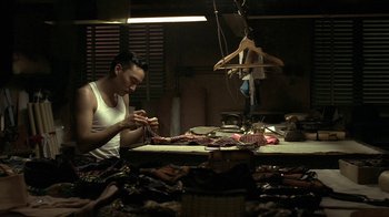 Movie still from “The Hand” (2004), directed by Kar-Wai Wong – A man sitting at a sewing table in a room; Medium shot, Low angle
