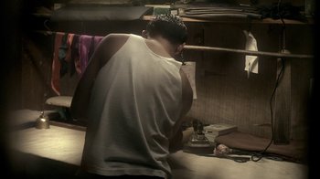 Movie still from “The Hand” (2004), directed by Kar-Wai Wong – A man standing in front of an ironing board in a kitchen; Medium shot, Low angle