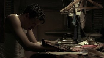 Movie still from “The Hand” (2004), directed by Kar-Wai Wong – A man sitting at a table in front of a pair of shoes; Medium shot, Low angle