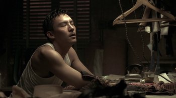 Movie still from “The Hand” (2004), directed by Kar-Wai Wong – A man sitting on a bed with his eyes closed; Close Up shot, Low angle