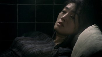 Movie still from “The Hand” (2004), directed by Kar-Wai Wong – A woman is laying down in a dark room; Close Up shot, High angle