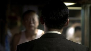 Movie still from “The Hand” (2004), directed by Kar-Wai Wong – A man wearing a suit is looking into a mirror; Close Up shot, Over the shoulder angle