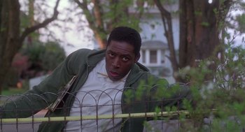 Movie still from “The Hand That Rocks the Cradle” (1992), directed by Curtis Hanson – A man leaning on a fence in front of a house; Medium shot, Low angle