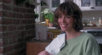 Movie still from “The Hand That Rocks the Cradle” (1992), directed by Curtis Hanson – A woman smiles while holding a towel; Close Up shot, Over the shoulder angle