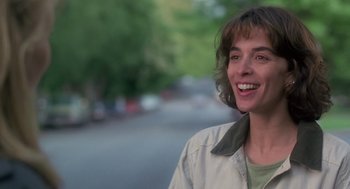 Movie still from “The Hand That Rocks the Cradle” (1992), directed by Curtis Hanson – A woman smiling while standing on the side of a road; Close Up shot, Over the shoulder angle