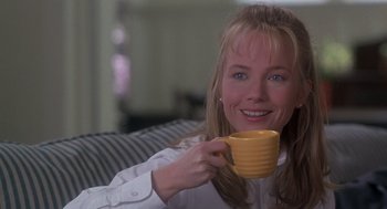 Movie still from “The Hand That Rocks the Cradle” (1992), directed by Curtis Hanson – A woman sitting on a couch holding a yellow cup; Close Up shot, Over the shoulder angle