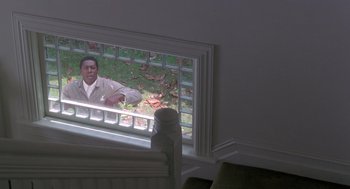 Movie still from “The Hand That Rocks the Cradle” (1992), directed by Curtis Hanson – A man looking out of a window in a room; Wide shot, High angle