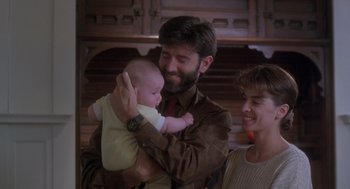 Movie still from “The Hand That Rocks the Cradle” (1992), directed by Curtis Hanson – A man holding a baby in his arms while standing next to a woman; Medium shot, Low angle