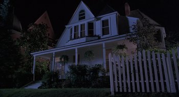 Movie still from “The Hand That Rocks the Cradle” (1992), directed by Curtis Hanson – A house with a white picket fence in front of it at night; Wide shot, Low angle