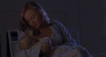 Movie still from “The Hand That Rocks the Cradle” (1992), directed by Curtis Hanson – A woman holding a baby in her arms in a dark room; Close Up shot, Over the shoulder angle