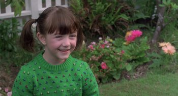 Movie still from “The Hand That Rocks the Cradle” (1992), directed by Curtis Hanson – A young girl in a green sweater smiling for the camera; Close Up shot, High angle