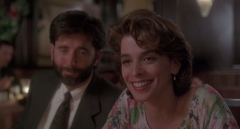 Movie still from “The Hand That Rocks the Cradle” (1992), directed by Curtis Hanson – A man and a woman smiling for the camera; Close Up shot, Over the shoulder angle