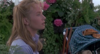 Movie still from “The Hand That Rocks the Cradle” (1992), directed by Curtis Hanson – A woman sitting in front of a flower bush; Close Up shot, Over the shoulder angle