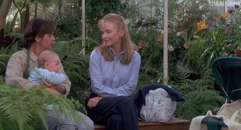 Movie still from “The Hand That Rocks the Cradle” (1992), directed by Curtis Hanson – A woman sitting on top of a bench next to a baby; Medium shot, Over the shoulder angle