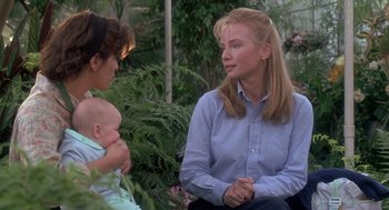 Movie still from “The Hand That Rocks the Cradle” (1992), directed by Curtis Hanson – Two women and a baby are sitting in a garden; Medium shot, Over the shoulder angle