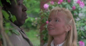 Movie still from “The Hand That Rocks the Cradle” (1992), directed by Curtis Hanson – A woman standing next to a man in front of a bush; Close Up shot, Low angle