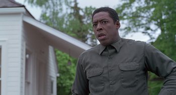 Movie still from “The Hand That Rocks the Cradle” (1992), directed by Curtis Hanson – A man in a green shirt is standing in front of a house; Close Up shot, Low angle