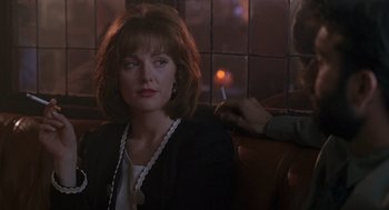 Movie still from “The Hand That Rocks the Cradle” (1992), directed by Curtis Hanson – A woman sitting in a booth with a cigarette in her mouth; Close Up shot, Over the shoulder angle