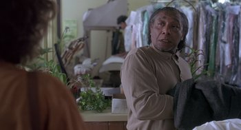 Movie still from “The Hand That Rocks the Cradle” (1992), directed by Curtis Hanson – An older man standing in front of a counter; Medium shot, Over the shoulder angle