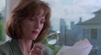 Movie still from “The Hand That Rocks the Cradle” (1992), directed by Curtis Hanson – A woman holding a magnifying glass in her hand; Close Up shot, Low angle