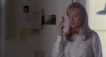 Movie still from “The Hand That Rocks the Cradle” (1992), directed by Curtis Hanson – A woman talking on a phone while wearing a white dress shirt; Medium shot, Low angle