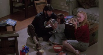 Movie still from “The Hand That Rocks the Cradle” (1992), directed by Curtis Hanson – A man and two girls sitting on the floor; Medium shot, High angle