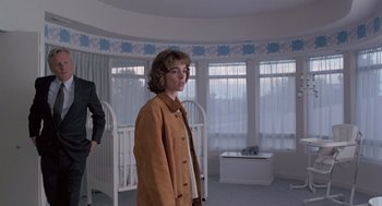 Movie still from “The Hand That Rocks the Cradle” (1992), directed by Curtis Hanson – A woman standing in front of a crib in a room; Medium shot, Low angle
