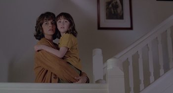 Movie still from “The Hand That Rocks the Cradle” (1992), directed by Curtis Hanson – A woman and a child are sitting on a stair railing; Medium shot, Low angle