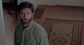 Movie still from “The Hand That Rocks the Cradle” (1992), directed by Curtis Hanson – A man in a green shirt is standing in a room; Close Up shot, Over the shoulder angle