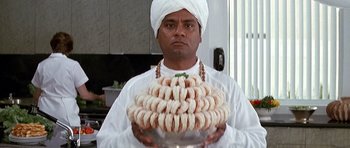 Movie still from “The Hard Way” (1991), directed by John Badham – A man in a white turban holding a plate of food; Close Up shot, Overhead angle