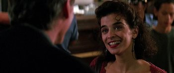 Movie still from “The Hard Way” (1991), directed by John Badham – A woman smiling at the camera while a man looks at her; Close Up shot, Over the shoulder angle